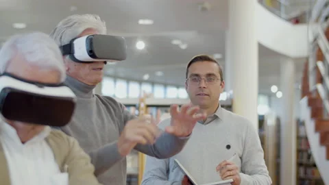 Elderly people in VR glasses in library with teacher Stock-Footage 232622949