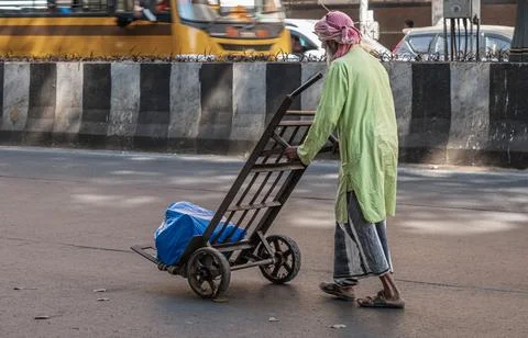 An elderly poor local man pushing heavy metal trolley through the street of M Stock Photos