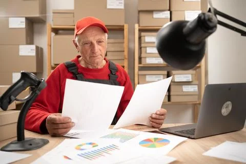 Elderly postal worker managing logistics accounting paperwork indoors 写真素材