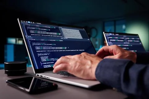 Elderly Programmer Codes In Office Late At Night On Laptops. Foto stock