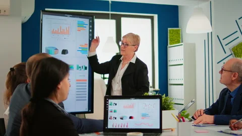 Elderly project manager pointing at desktop presenting statistical data, Stock Footage 147653881