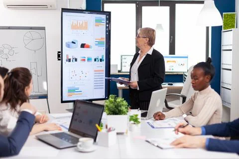 Elderly project manager pointing at desktop presenting statistical data Stock Photos