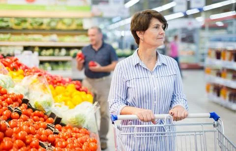 Elderly retired senora buying tomatoes in grocery section of the supermarket Stock Photos