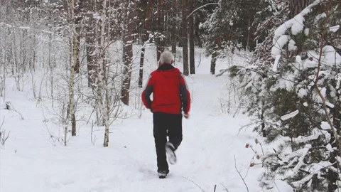 Elderly running man through a snowy forest Stock Footage 100445662