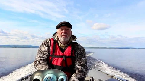 Elderly sailor with beard in life jacket drives sailing inflatable boat on lake Stock Footage 141493934