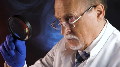 Elderly scientist looking through a magnifying glass Stock Footage 130344207
