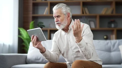 Elderly senior gray haired man having a video call with a doctor using a digital Stock Footage 256714300