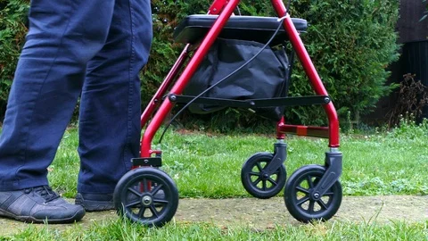 Elderly / senior man pushing a rollator / adult stroller outside. Video stock 100459573