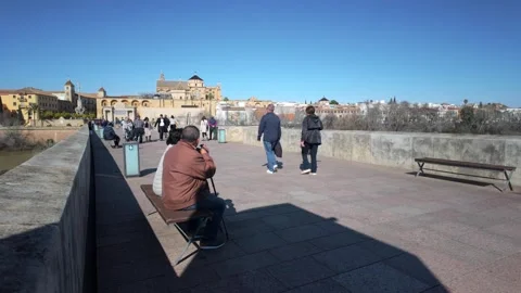 Elderly senior seating on the bench and tourists passing by, Cordoba, Spain - 4K 스톡 동영상 331402664