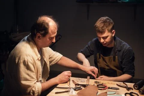 An elderly shoemaker and his apprentice create shoes by hand in their workshop Stock-Fotos