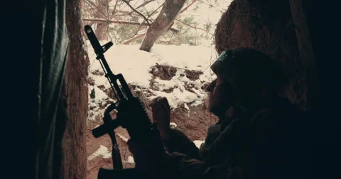 An elderly soldier sits with a machine gun in a trench, dugout and smokes. Stock Footage 260468752