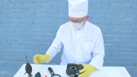 Elderly solid person in white dressing gown, cap, medical mask, glasses clean Stock Footage 93428869