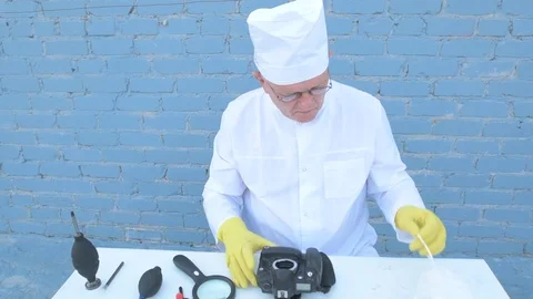 Elderly solid person in white dressing gown, cap, medical mask, glasses clean Stock Footage 93428966