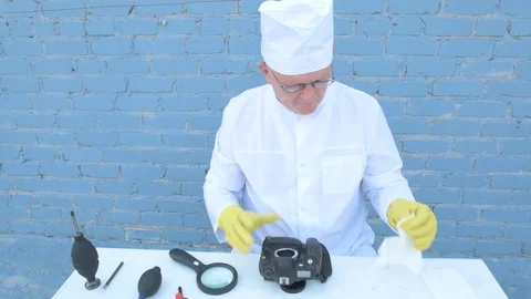 Elderly solid person in white dressing gown, cap, medical mask, glasses clean Stock Footage 93429025