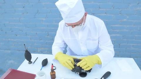 Elderly solid person in white dressing gown, cap, medical mask, glasses clean Stock Footage 93429070