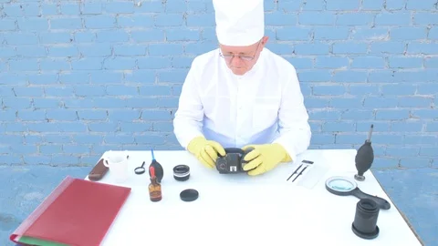 Elderly solid person in white dressing gown, cap, medical mask, glasses clean Stock Footage 93429518