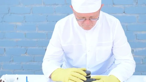 Elderly solid person in white dressing gown, cap, medical mask, sensor cleans Stock Footage 93429536