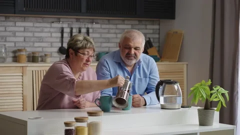 Elderly spouses are drinking tea at weekend, sitting at home kitchen, spending Stock Footage 153401462