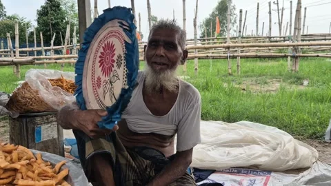 Elderly Street Vendor Using Hand Fan In Hot Weather In Bangladesh Vidéo 338437427