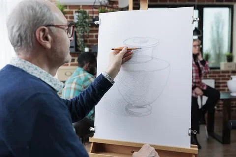 Elderly student drawing vase model on white canvas using sketching technique Foto stock