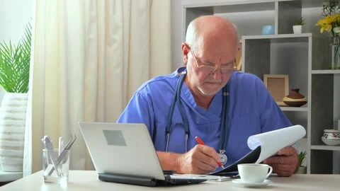 An elderly surgeon works in an office with a computer and documents Stock Footage 289095047