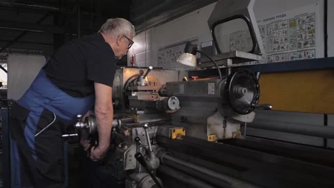 Elderly technician adjusts a lathe on a rolling mill Stock Footage 212401816