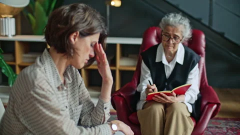 Elderly Therapist Taking Notes during Psychology Consultation with Woman Stock Footage 317733879