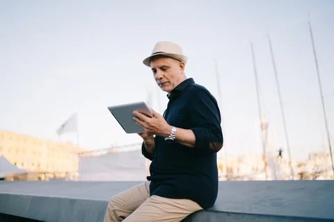 Elderly tourist using digital tablet for browsing publication and make booking Stock Photos