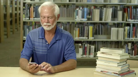 Elderly using cellphone in library Stock-Footage 67365115