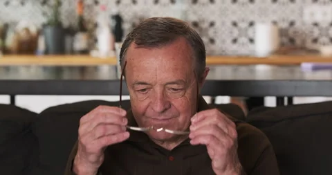 Elderly, visually impaired man puts on glasses, close-up, portrait. Concept of Vidéo 277686388