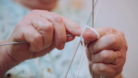 Elderly white grandma knitting with multiple needles, closeup hands forming Stock Footage 334791774