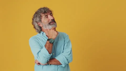 Elderly white-haired man makes a difficult decision, isolated on orange Stock Footage 255505317
