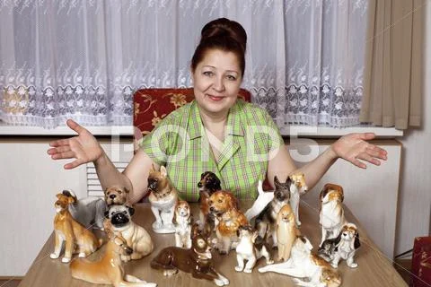 Elderly woman with a collection of porcelain figurines of dogs Stock Photos