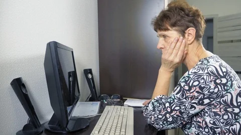 Elderly woman at the computer sits at a table in the home office Stock Footage 123293374