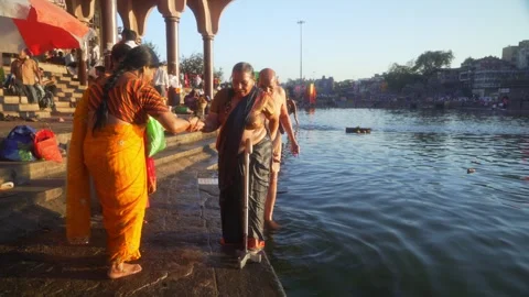 Elderly woman devotee with walking stick after holy bath at Ganga Ghat Stock Footage 314706956