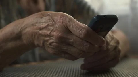 Elderly woman dialing number on push-button mobile phone. Hands close-up. Stock Photos