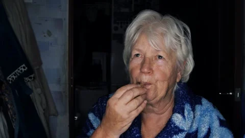 An elderly woman eats and gnaws on a chicken bone. Social inequality Stock Footage 293364544