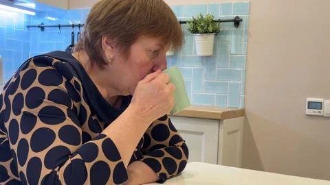 An elderly woman eats sitting at the table. Stock Footage 309520085