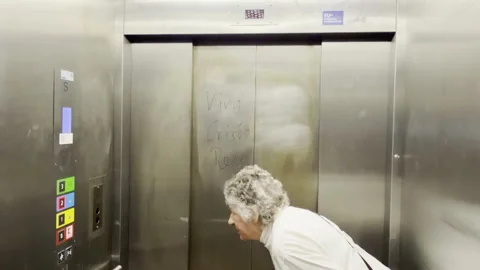 An elderly woman is in an elevator, she is looking for the right button Stock Footage 332975826