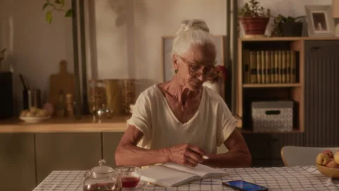 Elderly Woman with Glucose Patch Checking Blood Sugar and Writing in Notebook 스톡 동영상 320974050