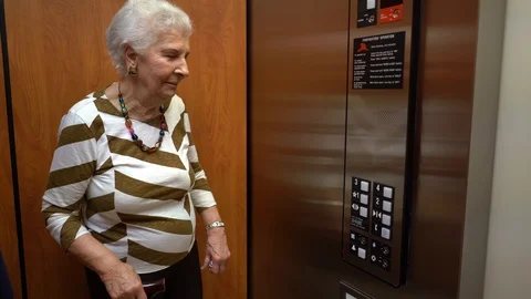 Elderly woman inside an elevator pushes the down button. Stock Footage 117130957