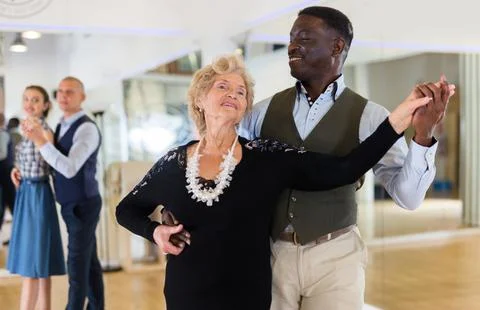 Elderly woman learning ballroom dancing in pair in dance studio Stock Photos