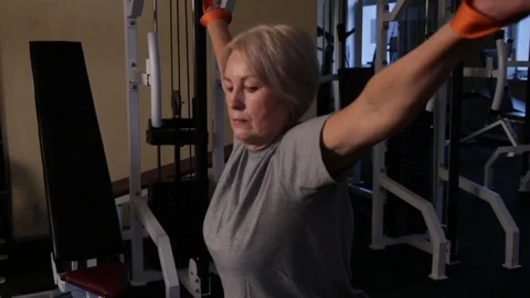Elderly woman performs kinesiological exercise.twisting on a crossover simulator Stock Footage 115851953
