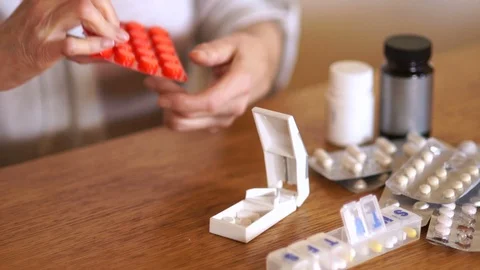 Elderly woman pulls a tablet from the package and divides into parts using a Stock Footage 104910886