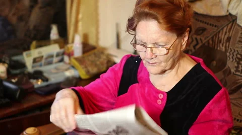 Elderly woman reading a newspaper while sitting on couch Stock Footage 61414853