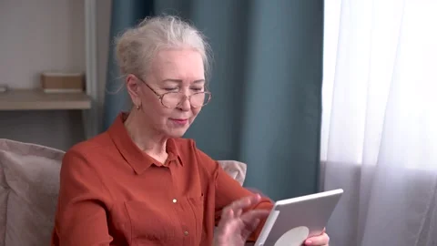 Elderly woman smiling while using a tablet Stock-Footage 297949299