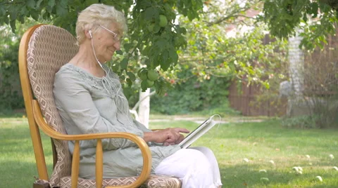 Elderly woman switches the music on the tablet. Stock Footage