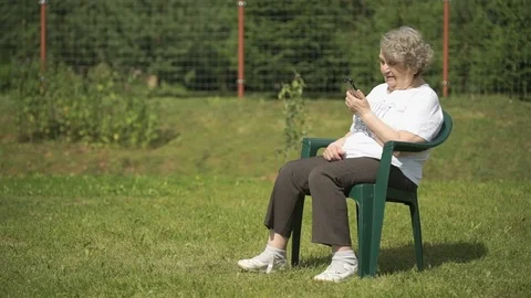 Elderly woman talking using a smart phone outdoors Stock Footage