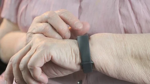 Elderly woman touches wristband of pulse monitor Stock Footage
