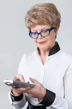Elderly woman understanding the television remote from the modern tv, grey ba Stock Photos